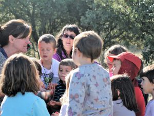 niñas y niños del grupo de juego Aúlla, de Moralzarzal escuchando una explicación de una educadora